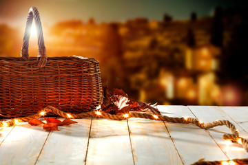 White wooden table background with brown basket and light bulbs. Blurred background and empty space for text decoration.