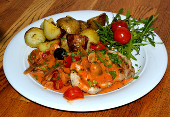 Dish with fried meat, vegetables, baked potatoes and fresh herbs and cherry tomato