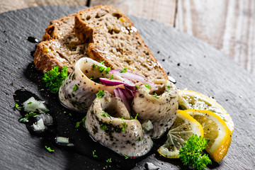 Marinated herring fillets with slices of bread on black stone