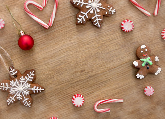 Christmas decoration. Christmas gingerbread, candy canes, caramel candy, red christmas ball on a wooden background with space for text. Top view, flat lay