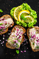 Marinated herring fillets on slices of bread on black stone