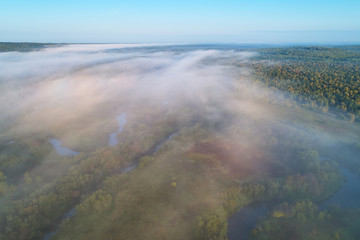 Aerial photography from the drone. Winding river and road in the forest in the morning fog