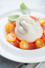 Close-up of burrata cheese with watermelon cubes and yellow cherry tomatoes, vertical shot