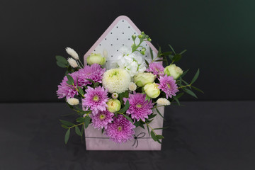 Composition of fresh flowers (chrysateme, rose, matiola. Colors light green, lilac) in a gift box in the form of an envelope