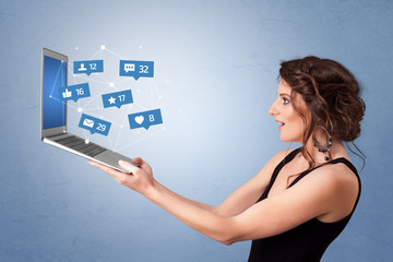 Woman holding laptop with different types of social media symbols and icons