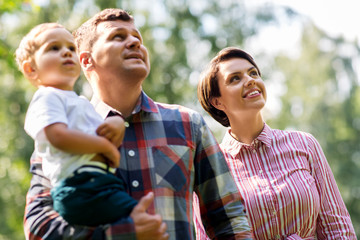 Fototapeta premium family, leisure and people concept - happy mother, father and little son at summer park