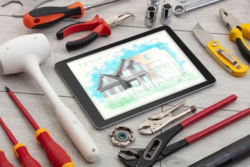 Tablet with construction tools and house plan concept