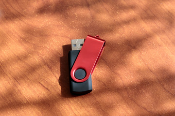 Black and red USB stick on brown wooden background