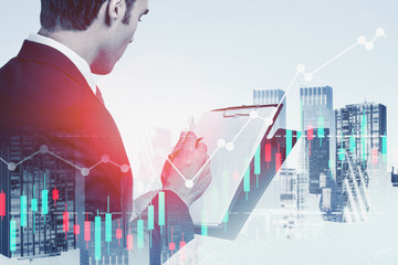 Businessman with clipboard in city, digital charts