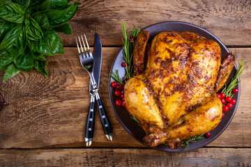 Baked chicken or turkey with herbs for festive dinner on wooden table. Christmas, Thanksgiving Day, holidays concept. Top view, copy space