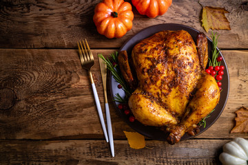 Baked chicken for Thanksgiving Day. Roasted whole chicken or turkey with herbs for thanksgiving dinner on wooden table. Thanksgiving Day, holiday, Christmas concept