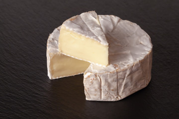 Camembert cheese is cut into pieces and whole.