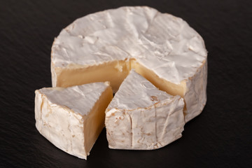 Camembert cheese is cut into pieces and whole.