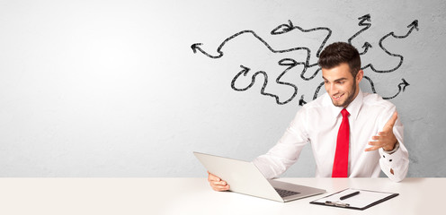 Businessman sitting at desk with direction concept