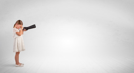 Cute little girl looking through spyglass to an empty space