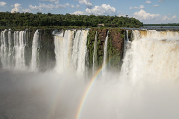 Landscape view of a rainbow over Devil's thoat (garganta del diablo) cascade at Iguazu waterfalls, Argentina on a sunny day