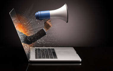 Hand with loudspeaker coming out of a laptop with sparkling effects