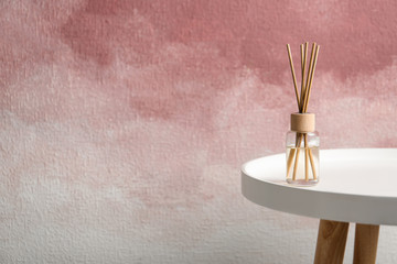 Reed air freshener on table against color background, space for text