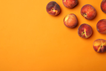 Flat lay composition with ripe peaches on orange background, space for text