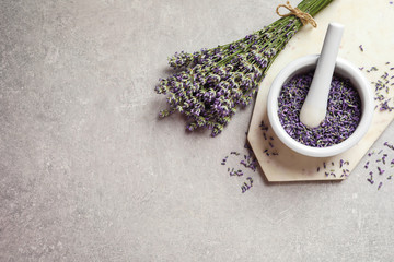 Top view of mortar and pestle with lavender flowers on grey stone background, space for text....