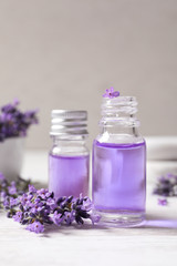 Fototapeta na wymiar Glass bottles of natural cosmetic oil and lavender flowers on white wooden table