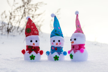 Three toy snowmen in the snow. A fun friendly company_