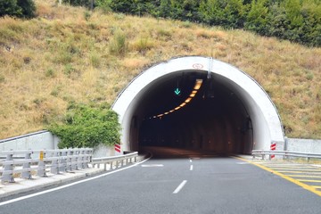 Road tunnel in mountains. Mountain road tunnel with luminous safety lights and yellow road line....