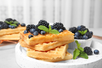 Delicious waffles with fresh berries served on kitchen table