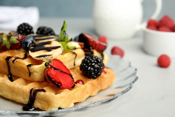Delicious waffles with fresh berries served on grey table, closeup. Space for text