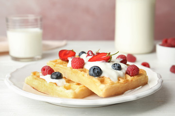 Delicious waffles with fresh berries served on white wooden table against pink background