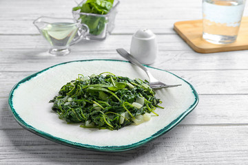 Tasty cooked spinach served on white wooden table. Healthy food