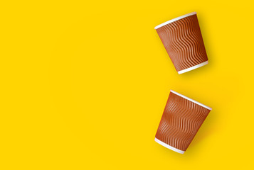 Coffee to go concept. Two paper cups of coffee on a yellow background. Template with copy space.