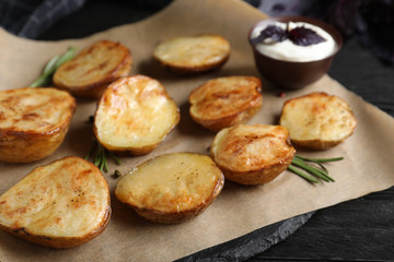 Obraz na płótnie Canvas Delicious potato wedges with sour cream on black wooden table, closeup