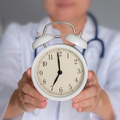 Doctor is holding alarm clock