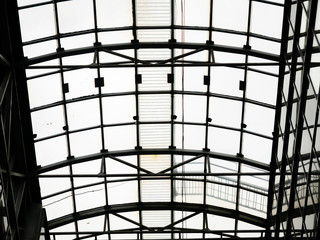 Openwork glazing of the roof over the shopping center. Ceiling in the form of a steel arch with glass windows. Bottom view on a cloudy day