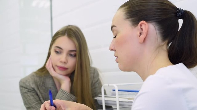 Professional cosmetologist. Female beauty doctor talking to her customer young woman while working in the beauty clinic. Cosmetology concept