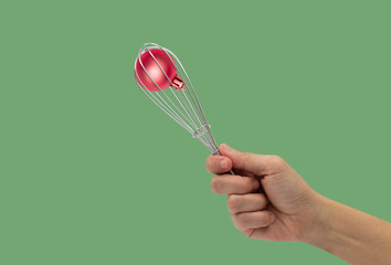 Female hand with a kitchen whisk and ball christmas isolated on