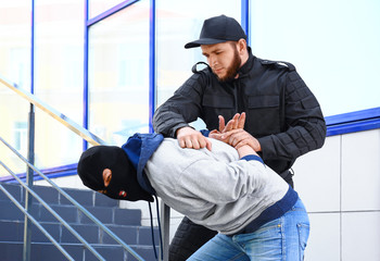 Police officer arresting masked criminal outdoors