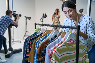 Stylist Choosing Clothes For Fashion To Wear On Photo Shoot In Studio
