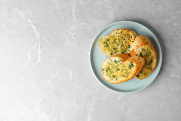 Slices of toasted bread with garlic, cheese and herbs on grey table, top view. Space for text