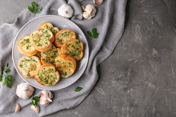 Slices of toasted bread with garlic and herbs on grey table, flat lay. Space for text