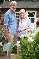 Portrait Of Mature Couple Working In Flower Beds In Garden At Home