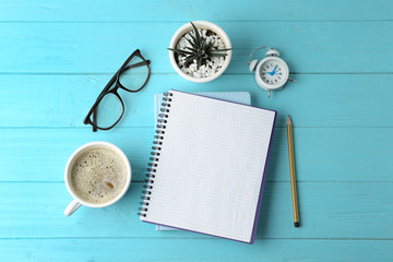 Flat lay composition with office stationery and cup of coffee on light blue wooden table. Space for text