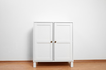 Wooden cabinet near white wall. Stylish home furniture