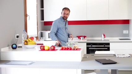 Man cuts fresh spring vegetables on the kitchen table.