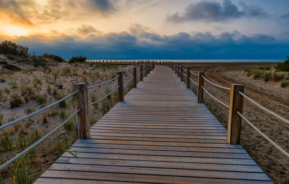 Wooden path in Riumar beach at sunset