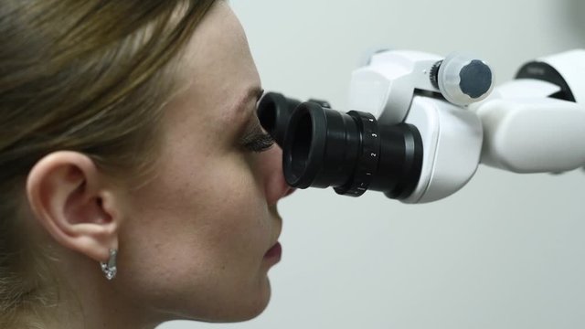 Doctor making teeth examination research survey using microscope in dentistry. Dentist is treating patient in modern dental office.