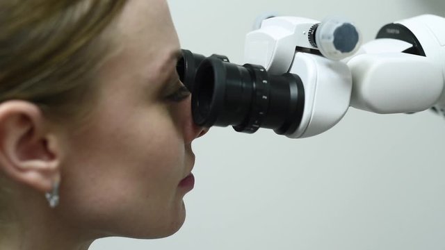 Doctor making teeth examination research survey using microscope in dentistry. Dentist is treating patient in modern dental office.