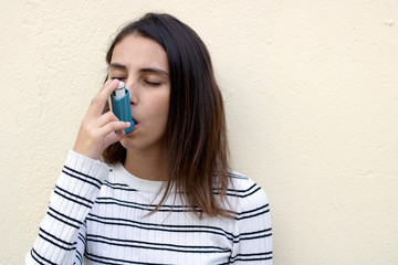 Health and medicine - Young girl using blue asthma inhaler.