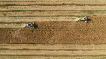Fototapeta na wymiar Aerial top down view shot of two combine harvester harvesting field
